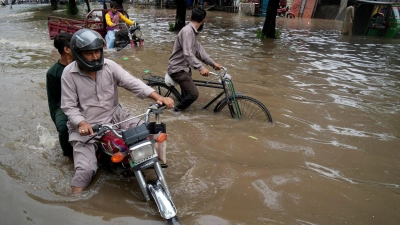 Motorradfahrer auf einer überschwemmten Straße im pakistanischen Lahore. (Foto: K.M. Chaudary/AP/dpa)