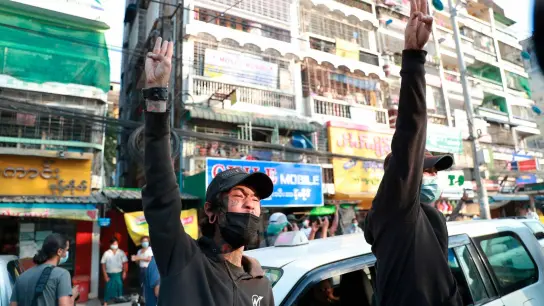Zwei Männer erheben im Februar 2021 die Hände zu einem Drei-Finger-Gruß - ein Zeichen des Widerstandes gegen den Militärputsch. (Foto: Str/AP/dpa)