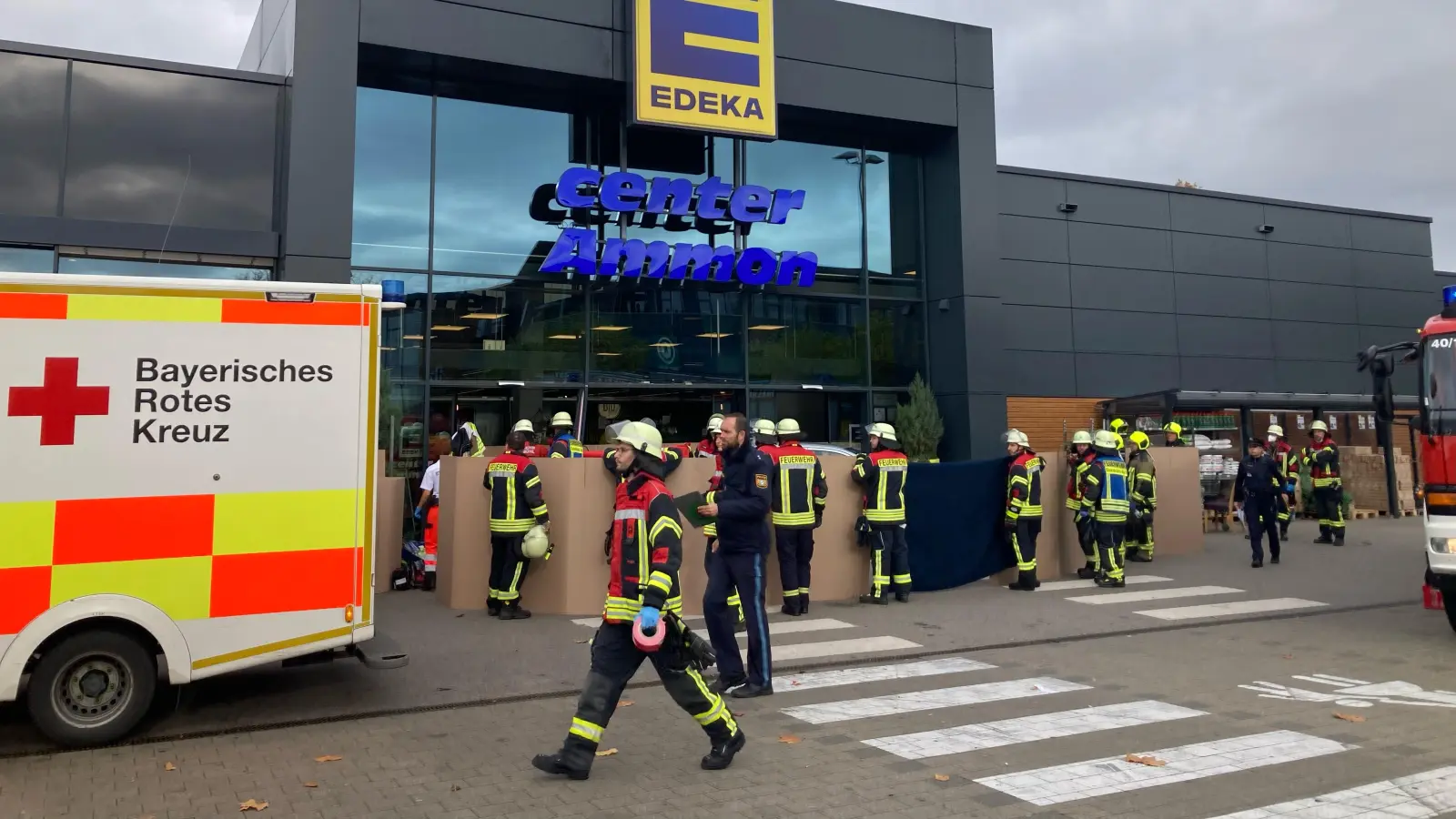 Bei einem Unfall an einem Supermarkt in Dinkelsbühl sind Polizei, Feuerwehr und Rettungskräfte im Einsatz. Mit Kartons wird von Feuerwehrkräften zunächst die Sicht auf den Unfallort vor dem Supermarkt verhindert. (Foto: Martina Haas)