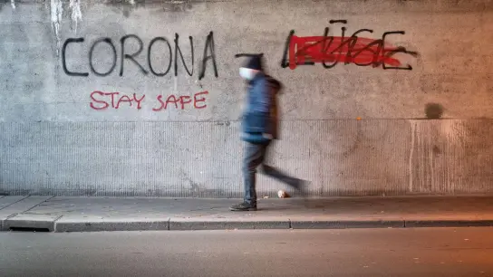 Ein Mann geht durch eine Offenbacher Eisenbahnunterführung, an deren Wand „Corona Lüge“ geschrieben steht. (Foto: Frank Rumpenhorst/dpa/Archivbild)