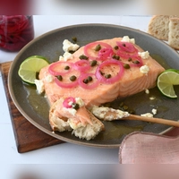 Die Marinade zum gegrillten Lachs sorgt für ein buttrig-süßes Aroma und bildet einen wunderbaren Kontrast zu den sauer eingelegten Zwiebeln und den salzigen Kapern.  (Foto: Julia Uehren/dpa-tmn)