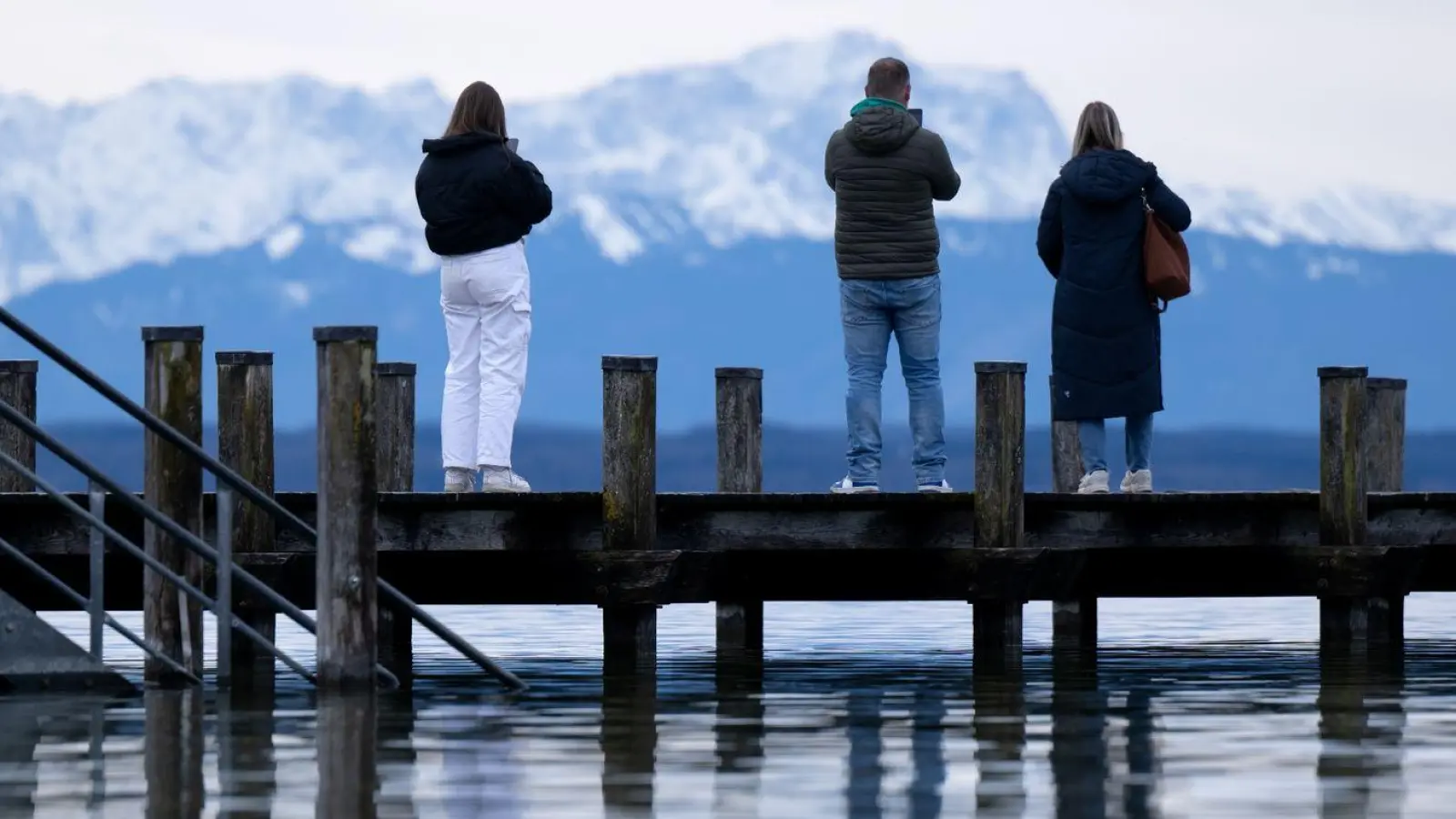 Menschen stehen auf einem Steg am Starnberger See. (Foto: Sven Hoppe/dpa)