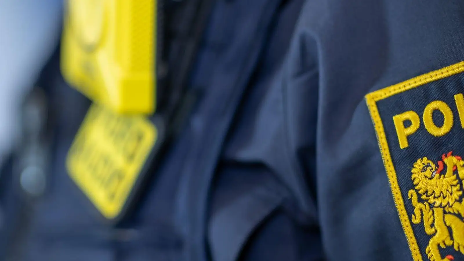 Eine Polizistin trägt ein Abzeichen der bayerischen Polizei. (Foto: Daniel Karmann/dpa/Symbolbild)