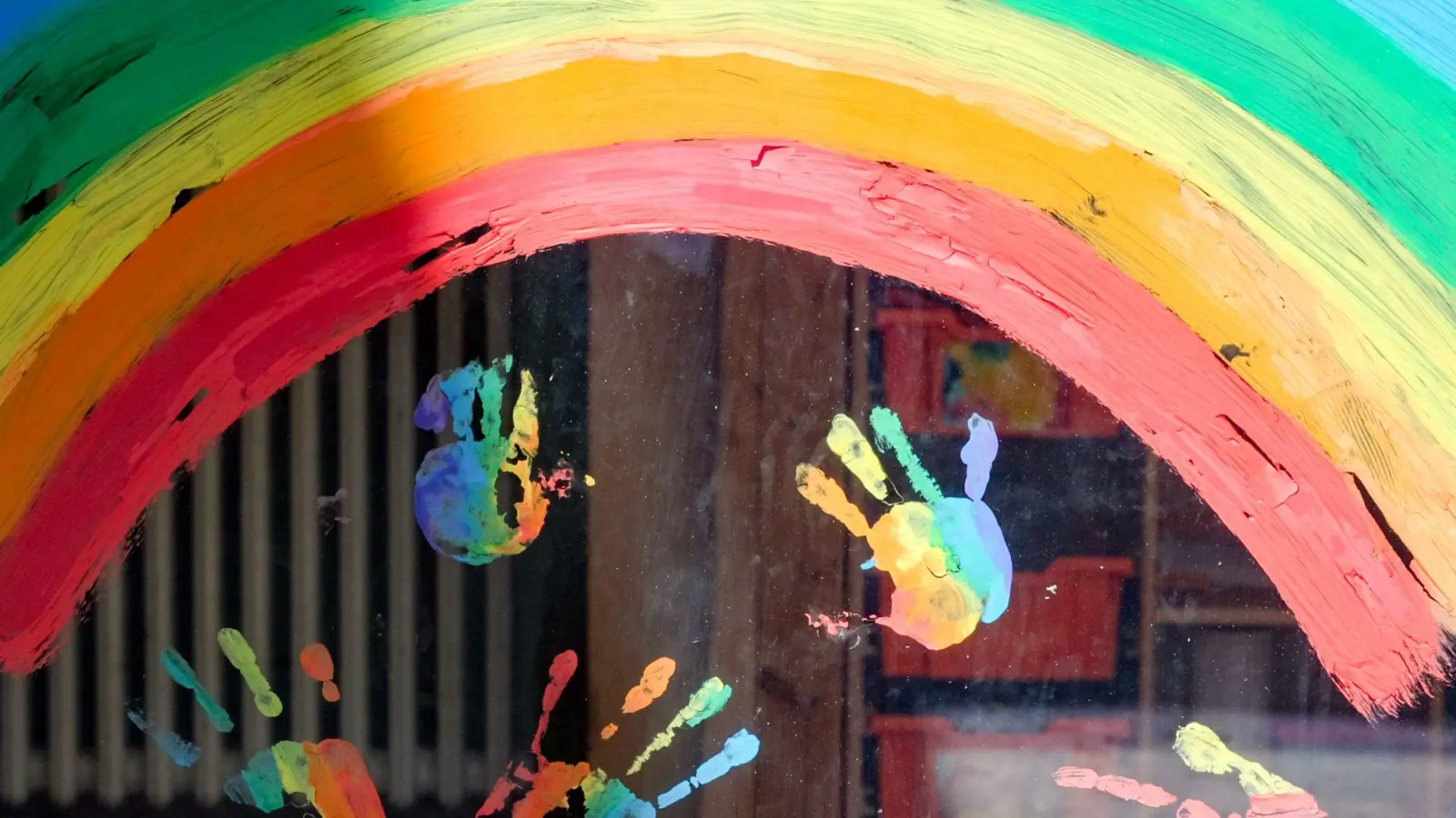 Kinderhände und ein Regenbogen am Fenster einer Kita. (Foto: Jens Kalaene/dpa-Zentralbild/dpa)