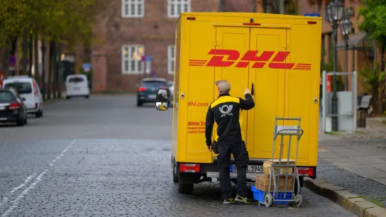 Ein Zusteller entlädt ein Fahrzeug von DHL in Lüneburg. (Foto: Philipp Schulze/dpa)