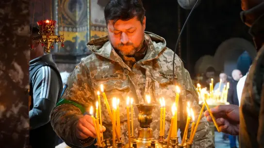 Ein ukrainischer Soldat entzündet Kerzen in der Wolodymyski-Kathedrale während der Osterfeierlichkeiten. (Foto: Efrem Lukatsky/AP/dpa)
