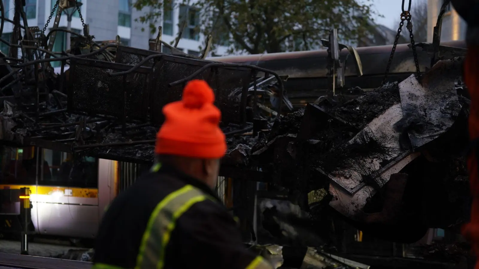 Spuren der Ausschreitungen in Dublin. Ein Arbeiter steht vor einer ausgebrannten Straßenbahn. (Foto: Brian Lawless/PA Wire/dpa)