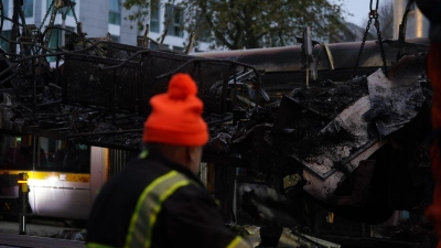 Spuren der Ausschreitungen in Dublin. Ein Arbeiter steht vor einer ausgebrannten Straßenbahn. (Foto: Brian Lawless/PA Wire/dpa)
