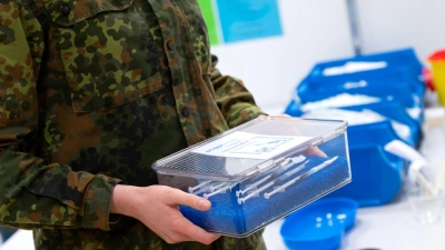 Eine Soldatin der Bundeswehr trägt im Impfzentrum eine Kiste mit Spritzen gegen das Coronavirus (Biontech). (Foto: Sven Hoppe/dpa/Archivbild)