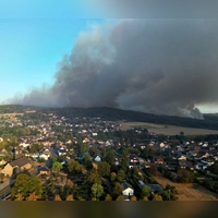 Rauch eines Waldbrands zieht über den Ortsteil Gey: Wenn das eigene Haus durch die Flammen Schaden nimmt, können Eigentümerinnen und Eigentümer auf ihre Wohngebäudeversicherung bauen. (Foto: Federico Gambarini/dpa/dpa-tmn)