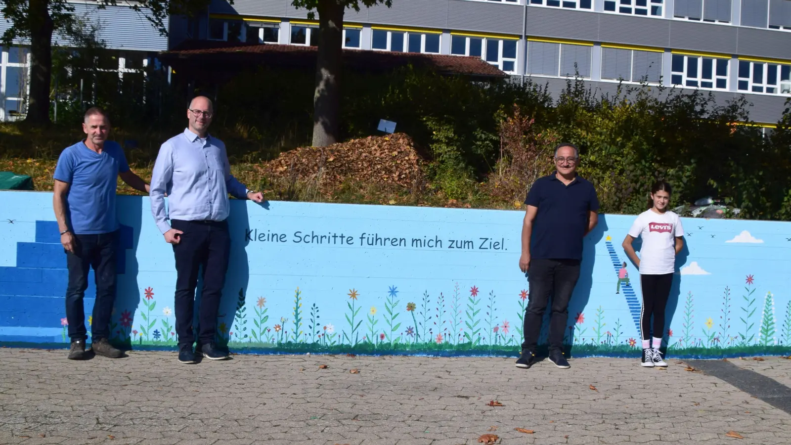 Mehrere Betonwände sind nun künstlerisch gestaltet. Das Bild zeigt (von links) Hausmeister Michael Lorenz, Bürgermeister Thomas Schmitt, Künstler Azar Valizada und Schülerin Laila Abd el Salam. (Foto: Gerhard Krämer)