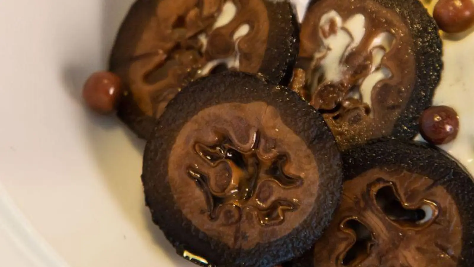 Schwarze Walnüsse in feine Scheiben geschnitten geben dem Vanilleeis mit Schokoladenkugeln einen Extra-Kick.  (Foto: Christin Klose/dpa-tmn)