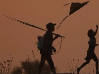Ein Junge (r) lässt einen Drachen steigen, während er mit seinem Vater nach dem Fischen am Stadtrand von Phnom Penh nach Hause geht. (Foto: Heng Sinith/AP/dpa)