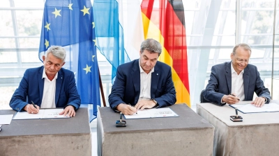 Ministerpräsident Markus Söder (CSU, M) unterzeichnet eine Vereinbarung für bevorstehende Veränderungsprozesse. (Foto: Matthias Balk/dpa)