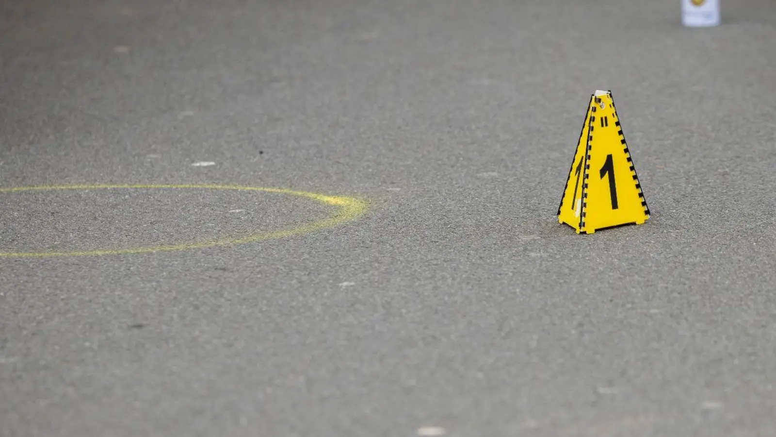 Markierungen der Spurensicherung auf dem Boden am Tatort des Angriffs auf zwei Kinder, einige Meter von einer Schule entfernt. Auf einem kleinen Parkplatz hat die Polizei Flatterband gespannt und alles abgesperrt. (Foto: Christoph Reichwein/dpa)
