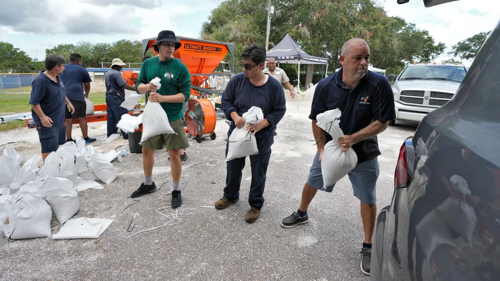 Mitarbeiter der Park- und Freizeitbehörde von Tampa in Florida helfen Anwohnern beim Verladen von Sandsäcken. (Foto: Chris O'Meara/AP)