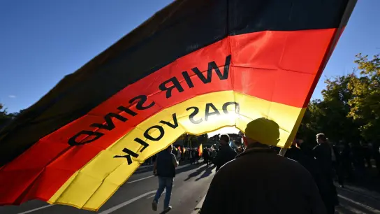 &quot;Wir sind das Volk&quot; steht auf einer Fahne, die ein Teilnehmer auf einer Kundgebung der Thüringer AfD im September trägt. (Foto: Martin Schutt/dpa)