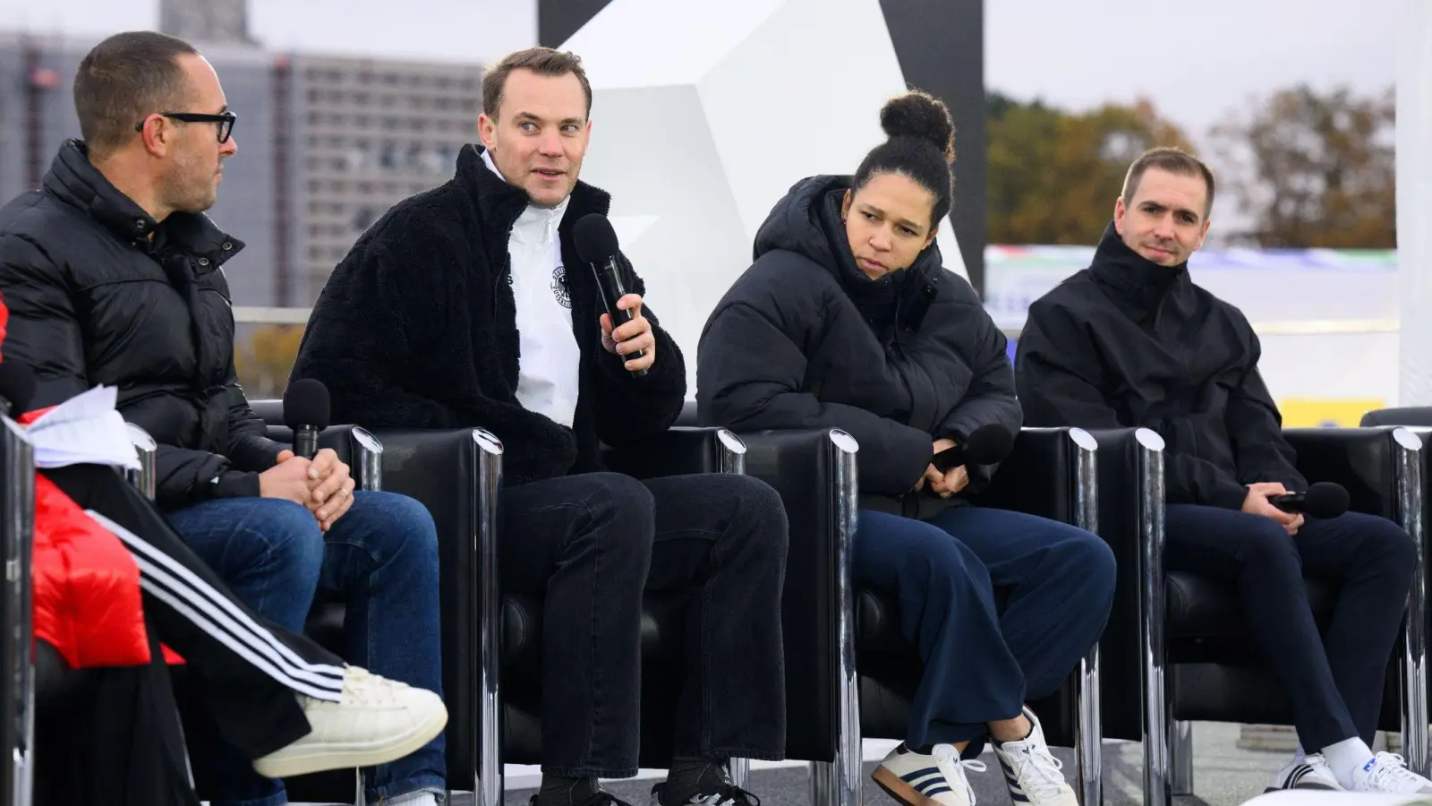 Sam Handy (l-r), Manuel Neuer, Célia Šašić und Philip Lahm sitzen im Olympiastadion. (Foto: Bernd von Jutrczenka/dpa)