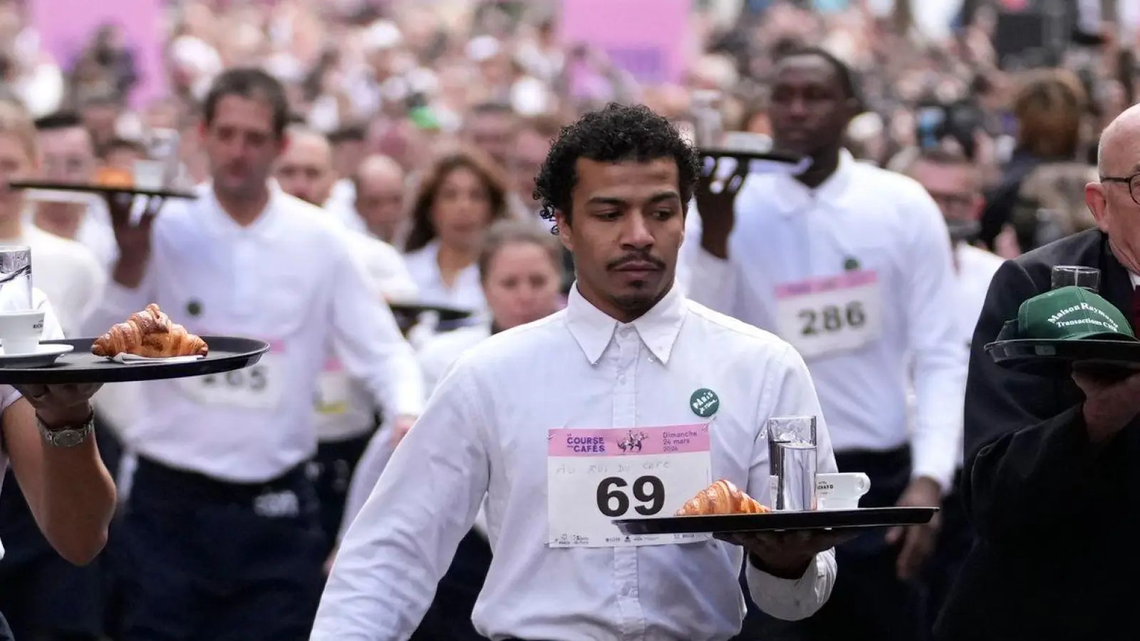 Zwei Kilometer ohne zu rennen und ohne etwas zu verschütten: Dieser Aufgabe stellen sich Kellnerinnen und Kellner in Paris. (Foto: Christophe Ena/AP/dpa)