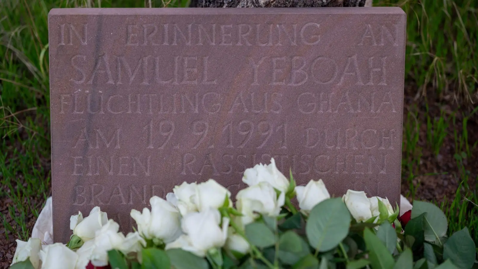 Teilnehmer der Gedenkkundgebung für den 1991 bei einem Brandanschlag getöteten ghanaischen Asylbewerber Samuel Yeboah haben an einem Gedenkstein Blumen abgelegt. (Foto: Harald Tittel/dpa)