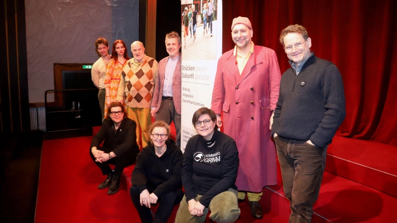 Die Stiftung gibt Kommando Grimm eine Spende. Im Saal der Kammerspiele präsentiert sich Stiftungsrat Dr. Axel Jaksche (4. von links stehend) mit dem Team des Theaterprojekts. (Foto: Oliver Herbst)