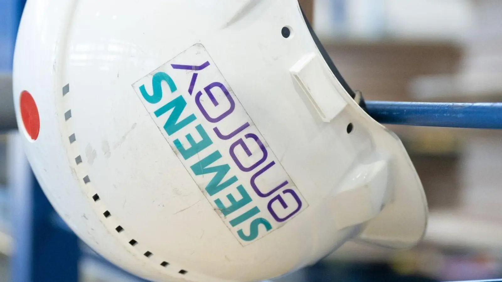 Ein Schutzhelm mit der Aufschrift „Siemens Energy“ hängt in einer Werkhalle im Transformatorenwerk Siemens Energy. (Foto: Sebastian Kahnert/dpa/Symbolbild)