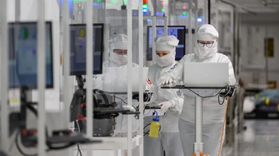 Mitarbeiter des Chipkonzerns Infineon arbeiten im Reinraum der Chipfabrik. (Foto: Robert Michael/dpa)