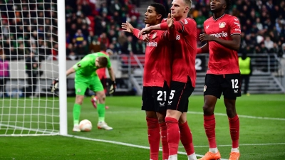 Leverkusens Torschütze Amine Adli (l-r) jubelt nach seinem Tor zum 0:2 mit Mitchel Bakker und Edmond Tapsoba. (Foto: Marton Monus/dpa)