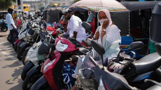 Menschen auf Motorrollern und Autorikschas warten an einer Tankstelle. Die Wirtschaftskrise in Sri Lanka hat dazu geführt, dass die 22 Millionen Einwohner des Landes mit einem Mangel an lebenswichtigen Gütern wie Medikamenten, Kraftstoff und Lebensmitteln zu kämpfen haben. (Foto: Eranga Jayawardena/AP/dpa)