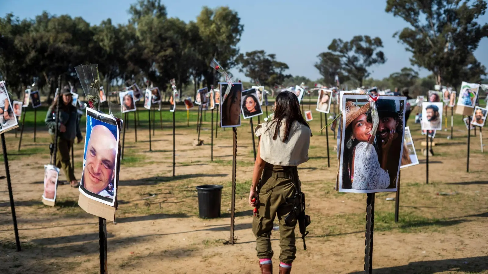 Israelische Soldatinnen stehen zwischen Fotos getöteter Israelis am Ort des Hamas-Massakers beim Musikfestival in der Negev-Wüste am 7. Oktober. (Foto: Ilia Yefimovich/dpa)