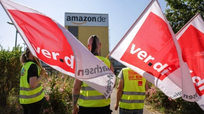 Streikende stehen mit Verdi-Flaggen vor einem Verteilzentrum des Online-Händlers Amazon in Leipzig (Archivbild). (Foto: Jan Woitas/dpa)