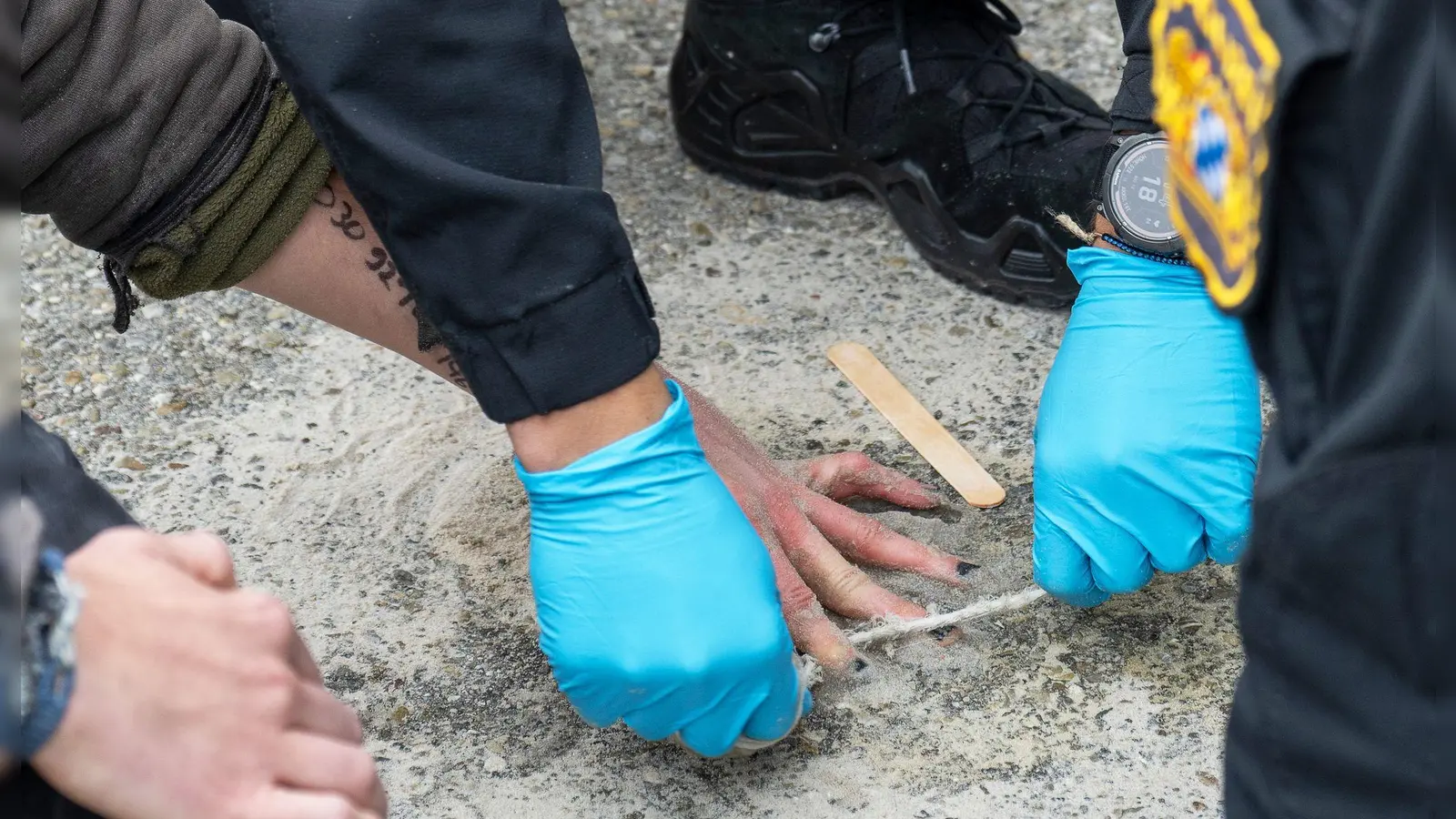 Speziell geschulte Polizisten versuchten, die Hände von Demonstranten von der Straße zu lösen. (Foto: Stefan Puchner/dpa)