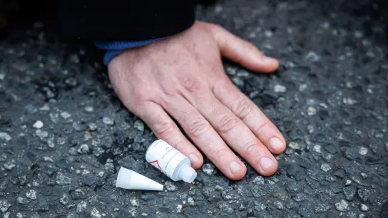 Ein Klimaaktivist hat sich am Stachus mit seiner Hand auf die Straße geklebt. (Foto: Matthias Balk/dpa)