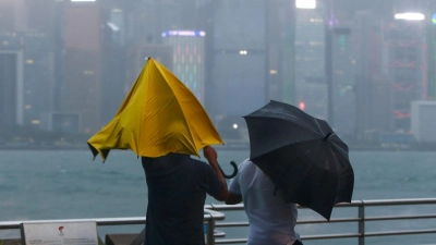Menschen mit Regenschirmen kämpfen in Hongkong gegen starken Wind und Regen des Taifuns „Saola“ an. (Foto: Daniel Ceng/AP/dpa)