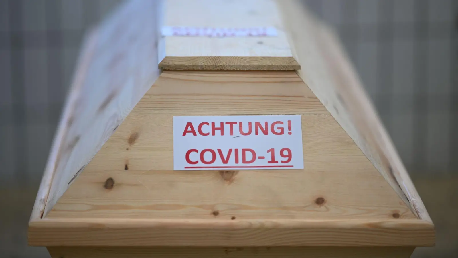 Ein Sarg mit der Aufschrift „Achtung! Covid-19“ in einem Raum im Krematorium, bevor der Sarg eingeäschert wird. (Foto: Felix Kästle/dpa)