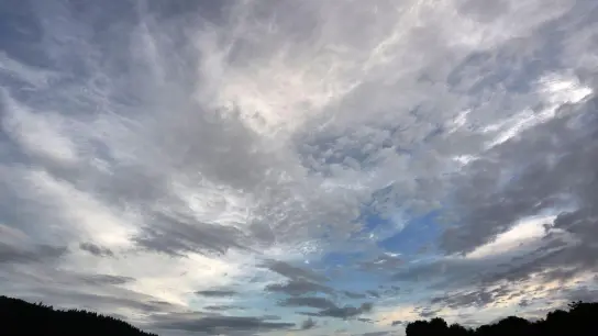 Eine aufreißende Wolkendecke zieht über eine Wiese hinweg. (Foto: Thomas Frey/dpa/Symbolbild)