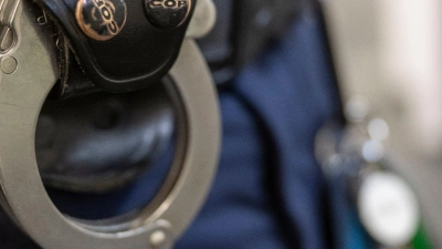 Eine Handschelle hängt am Gürtel eines Polizisten der Polizeiinspektion 11. (Foto: Peter Kneffel/dpa)