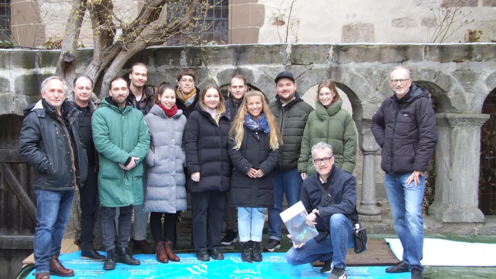 Gruppenfoto mit Bürgermeister Patrick Ruh (vorne) und Intendant Johannes Kaetzler (rechts) auf der witterungsbedingt abgedeckten Bühne. Danach ging es für das „Dschungelbuch“-Ensemble sowie die Akteurinnen und Akteure hinter der Bühne wieder in die Schranne. (Foto: Jasmin Kiendl)