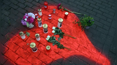 Kerzen und Blumen liegen in einem auf das Pflaster gesprühten roten Herzen in Düsseldorf nach dem mörderischen Brandanschlag. (Foto: Federico Gambarini/dpa)