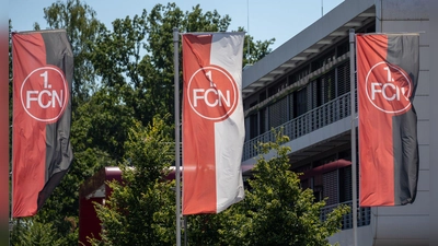 Fahnen mit dem FCN-Logo wehen vor dem Vereinsgebäude. (Foto: Daniel Karmann/dpa)