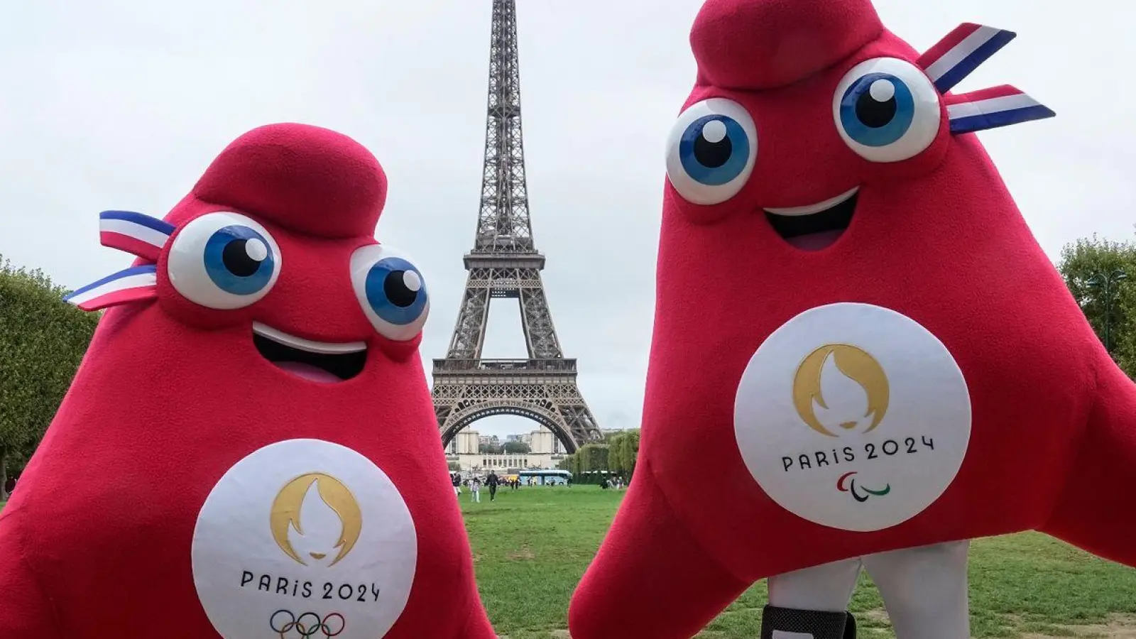 Die Maskottchen der Olympischen (l) und Paralympischen Spiele in Paris stehen vor dem Eiffelturm. (Foto: Michel Euler/AP/dpa)