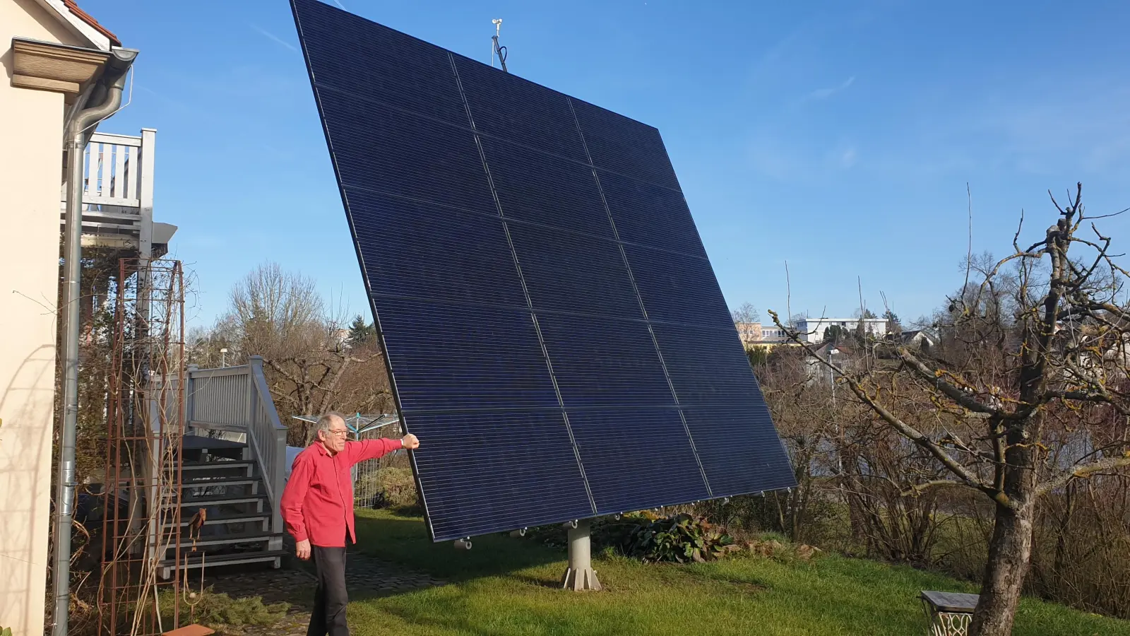 Geradezu winzig wirkt Tüftler Gerhard Schwab neben dem Photovoltaik-Segel in seinem Garten, das sich selbstständig nach der Sonne ausrichtet. Der Maschinenbauer hat die Technik selbst verfeinert. (Foto: Wolfgang Grebenhof)