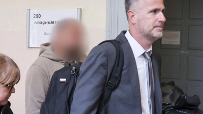 Der Zeuge (Mitte des Bildes) wird von seinem Anwalt (rechts im Bild) in den Gerichtssaal begleitet. (Foto: Christian Charisius/dpa)
