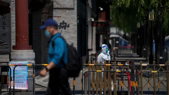 Ein Mann in Schutzkleidung steht im Mai vor geschlossenen Läden in Peking. (Foto: Andy Wong/AP/dpa)