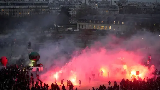 Demonstranten gehen am Ende der Demonstration gegen die geplante Heraufsetzung des Renteneintrittsalters in Paris durch Fackelrauch. (Foto: Thibault Camus/AP/dpa)