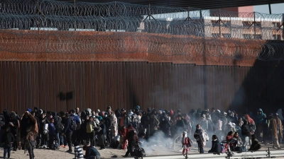 Migranten aus Lateinamerika stehen an der Grenzmauer zwischen Mexiko und den USA. (Foto: Christian Chavez/AP/dpa)