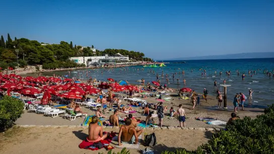 Badegäste sonnen sich am Strand Bacvice in Kroatien. Die rekordverdächtige Inflation und der Ukraine-Krieg scheinen die Reiselust der Menschen in Deutschland nach zwei Corona-Jahren nicht zu dämpfen. (Foto: Fernando Gutierrez-Juarez/dpa-Zentralbild/dpa)