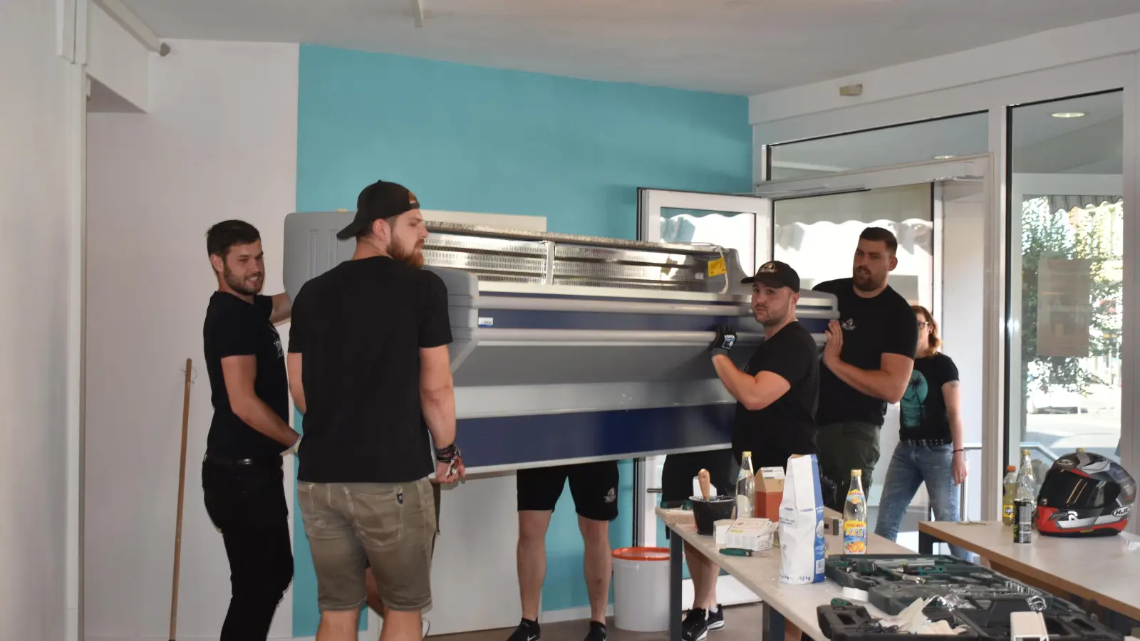 Starke Helfer waren gestern bei der Bestückung der neuen Tafel-Ausgabestelle gefragt. Kurzfristig sprangen die Footballer der Neustadt Falcons ein, trugen Kühltheke und später eine Kisten-Spülmaschine hinein. (F.: Ute Niephaus)
