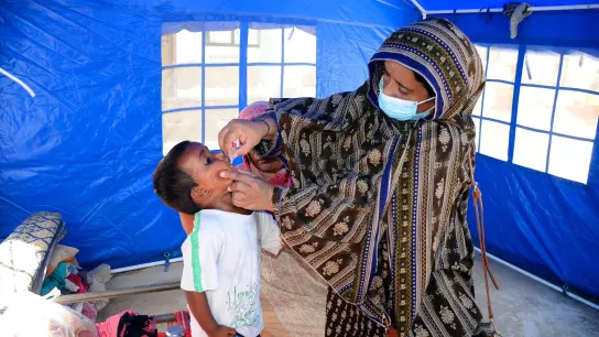 Nach den schweren Überschwemmungen in Pakistan verabreicht eine Mitarbeiterin des Gesundheitswesen einem Kind eine Schluckimpfung gegen Polio. (Foto: Pervez Masih/AP/dpa)