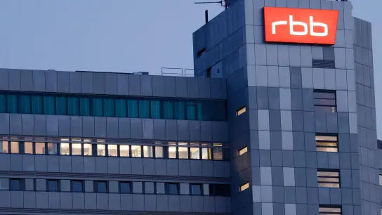Das beleuchtete Logo des Senders Rundfunk Berlin-Brandenburg (RBB) ist an der Fassade am Sitz des Senders an der Masurenallee angebracht. (Foto: Carsten Koall/dpa)